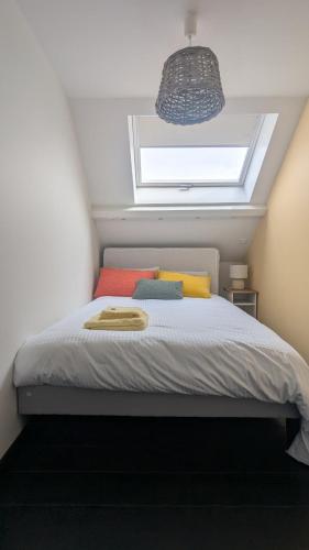 - une chambre avec un lit doté d'oreillers colorés et d'une fenêtre dans l'établissement Duplex terrasse place du Marché, à La Baule