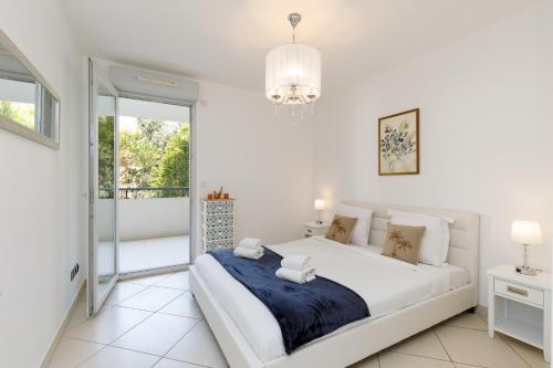 une chambre blanche avec un grand lit et un balcon dans l'établissement Fleury Home YourHostHelper, à Cannes
