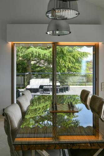 a living room with a table and a large window at Superbe villa avec piscine intérieure, sauna, jacuzzi et salle de sport in Lucinges