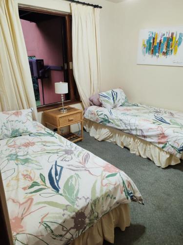 a bedroom with two beds and a table with a lamp at San Lameer Tropical Villa in Southbroom