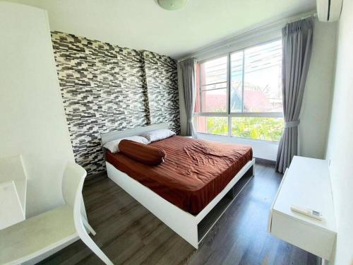 a bedroom with a bed and a brick wall at Cozy 1-Bedroom in D'vieng Condo in Chiang Mai