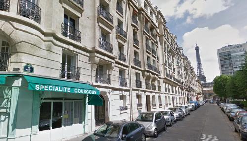 une rue avec des voitures garées à côté de bâtiments avec la tour Eiffel dans l'établissement Prêt à usage & Commodat 13 Finlay RDC- 30 nuitées minimum - Salarié mobilité ou étudiant stagiaire, à Paris