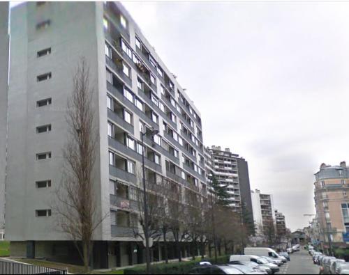 un grand bâtiment avec des voitures garées dans une ville dans l'établissement Prêt à usage & Commodat 13 Finlay RDC- 30 nuitées minimum - Salarié mobilité ou étudiant stagiaire, à Paris