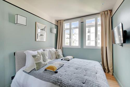 une chambre avec un grand lit avec des oreillers blancs dans l'établissement La Maison Bizot 43 T3 by ecoflats, à Paris