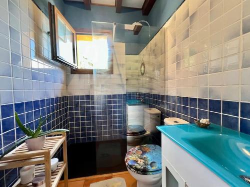 a blue tiled bathroom with a toilet and a sink at Secret Paradise, Stylish Host in Camargo