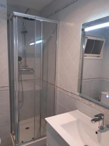 Un baño con ducha, lavabo y espejo. en Altafulla, primera linea de mar con acceso directo a la playa, en Altafulla