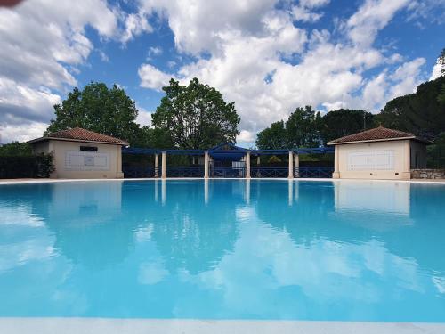 une grande piscine d'eau bleue avec deux bâtiments dans l'établissement La casa d'azur, à Tourrettes