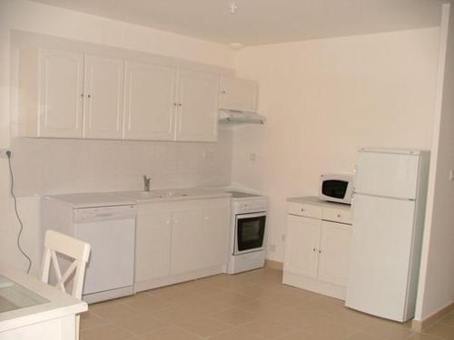 une cuisine avec des armoires blanches et un réfrigérateur blanc dans l'établissement maisons 6 personnes Royan piscine couverte, à Saint-Georges-de-Didonne