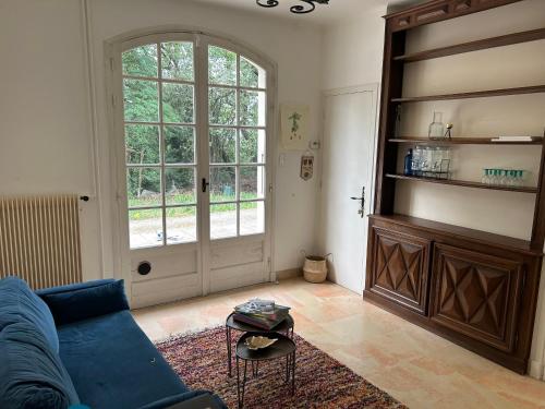 ein Wohnzimmer mit einer blauen Couch und einem großen Fenster in der Unterkunft Domaine Happyness en Ardèche in Le Teil