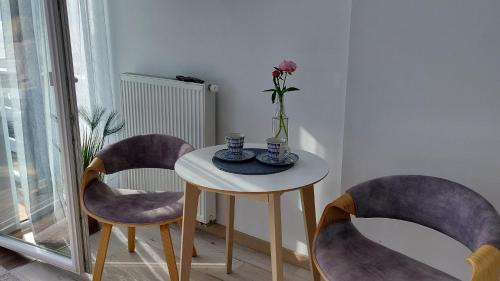 a table with two chairs and a vase with a flower on it at Pokoje na plaży in Ustronie Morskie