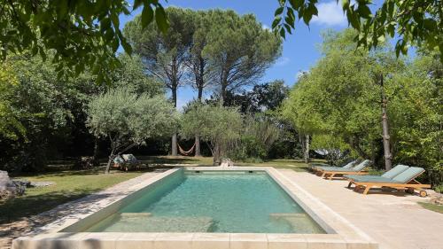 - une piscine dans une cour avec deux bancs et des arbres dans l'établissement Mas de Faviérette, gîte Les Voûtes et gîte La Terrasse, à Sabran