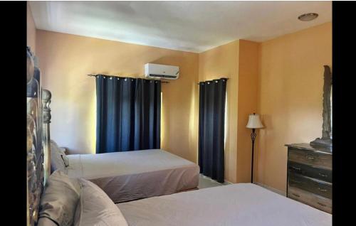 a bedroom with two beds and a dresser with curtains at Indigo Beach Villa in Black River
