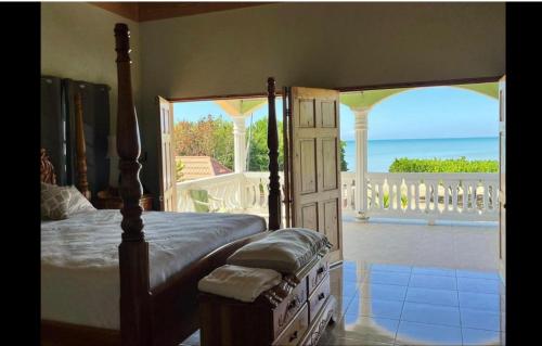 a bedroom with a bed and a view of the ocean at Indigo Beach Villa in Black River