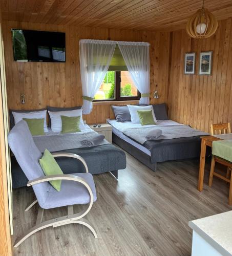 a bedroom with two beds and a chair and a table at Domki letniskowe "Kwatery u Skrzacika" in Sianozety