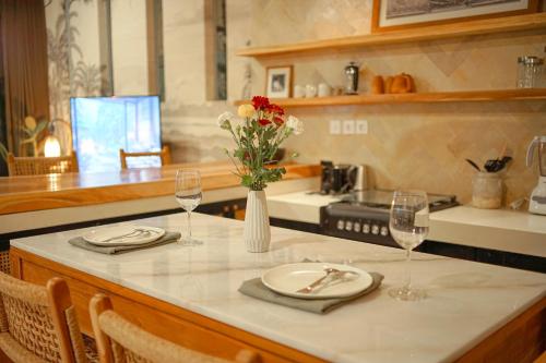 een keuken met een tafel met twee borden en wijnglazen bij Villa La Familia Dua in Canggu