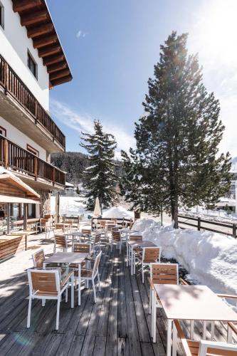 a row of tables and chairs on a deck in the snow at CHALET DES ALPES in Gressan