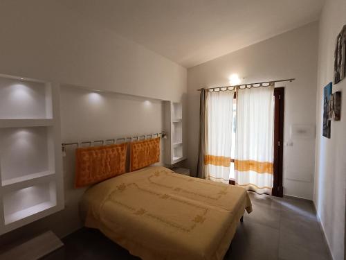 a bedroom with a bed and a large window at Su Suberju in San Teodoro