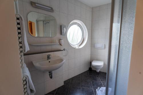 a bathroom with a sink and a mirror and a toilet at Airport Business Hotel Köln in Cologne