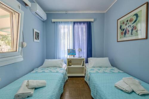 two beds in a room with blue walls at Rastoni - Beach Family House in Chorafakia