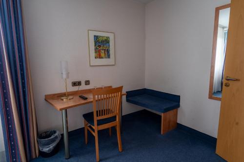 a room with a desk and a chair and a table at Airport Business Hotel Köln in Cologne