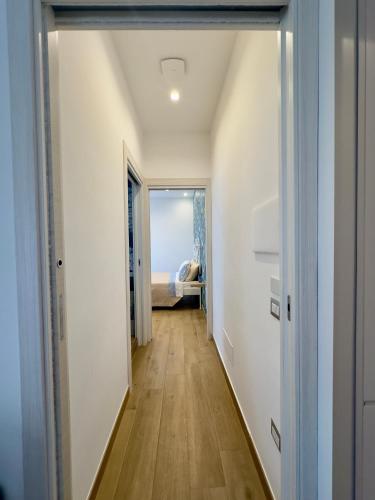 a hallway leading to a bedroom with white walls and wood floors at Blue House GM in Gragnano