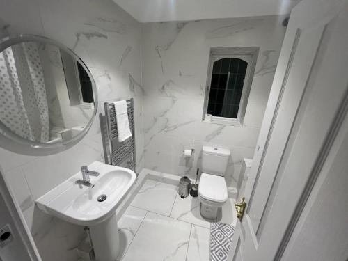 a white bathroom with a sink and a toilet at Big new house! 5BDR, sleeps 13, with parking in Carrington
