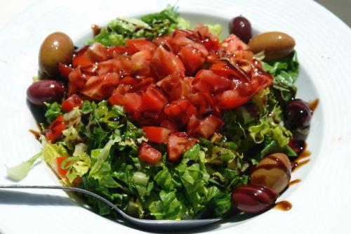 a salad with tomatoes and grapes on a plate with a spoon at Verdelis Inn in Ancient Epidavros