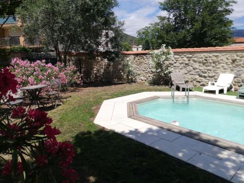 a pool with a chair and a table and flowers at Gîte de charme la belle histoire in Prades