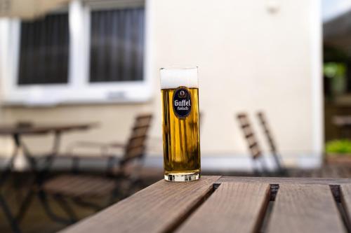 a glass of beer sitting on a wooden table at Airport Business Hotel Köln in Cologne