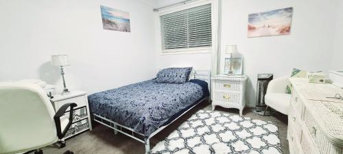 a bedroom with a bed and a chair and a window at Hills Bed & Breakfast in Pennant Hills