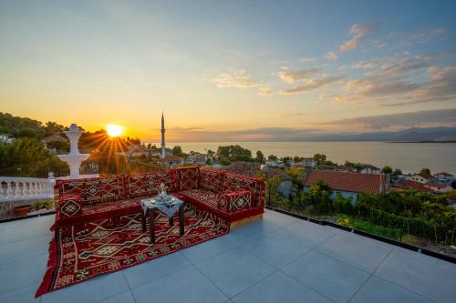 a balcony with a red bench and the sunset at Vila Sela in Shkodër