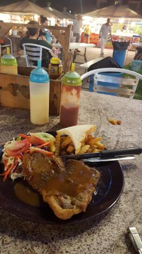 un plato de comida con carne y patatas fritas en una mesa en A101 The Ocean Pearl, en Pattaya South
