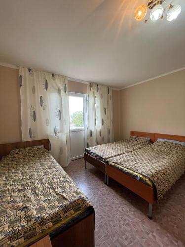 a room with two beds and a window at Отель на берегу in Bosteri