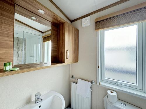 a bathroom with a toilet and a sink and a window at Stewarts Resort Lodge 2 in St. Andrews
