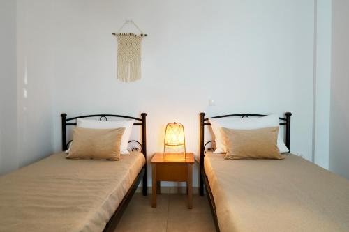 two beds in a room with a lamp on a table at Dimora Miranda in Agios Prokopios