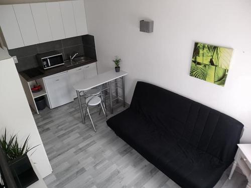- une cuisine avec un canapé noir dans une chambre dans l'établissement Studio Les pieds dans l'eau, à Mandelieu-la-Napoule