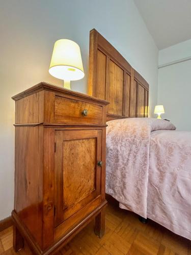 a bedroom with a bed with a wooden dresser and a lamp at La Casa dei Nonni in Alano di Piave