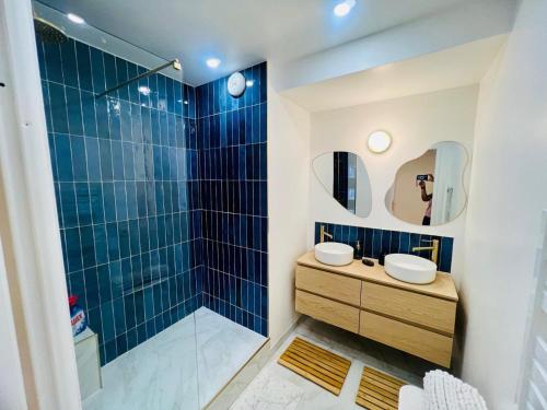 La salle de bains est pourvue de 2 lavabos et d'une douche avec du carrelage bleu. dans l'établissement Serenity Place, à Serris