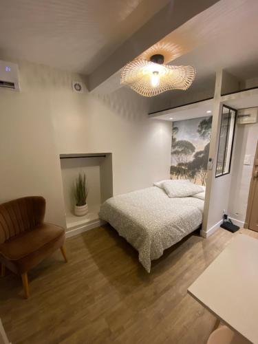 - une chambre avec un lit, une chaise et un lustre dans l'établissement Charmant studio hyper centre, à Bastia