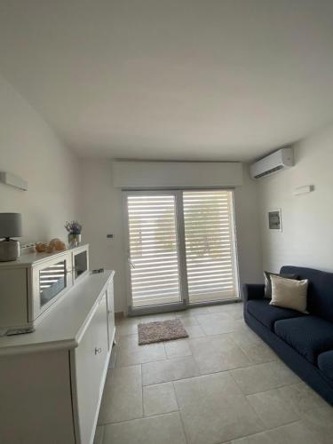 a living room with a blue couch and a kitchen at Country House in Torre San Giovanni Ugento