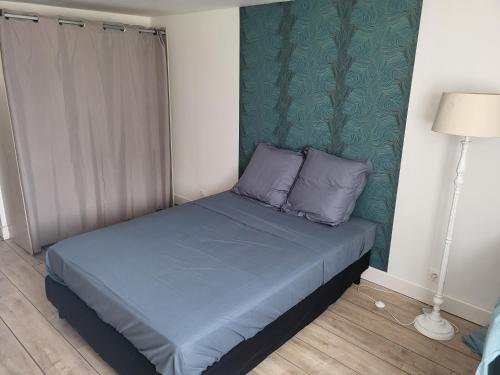 Cette petite chambre comprend un lit avec des oreillers bleus. dans l'établissement gitechezpetitjean, à Turretot