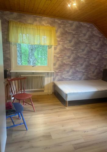 a bedroom with a bed and a window and a chair at Summer in the North of Sweden in Bjurholm
