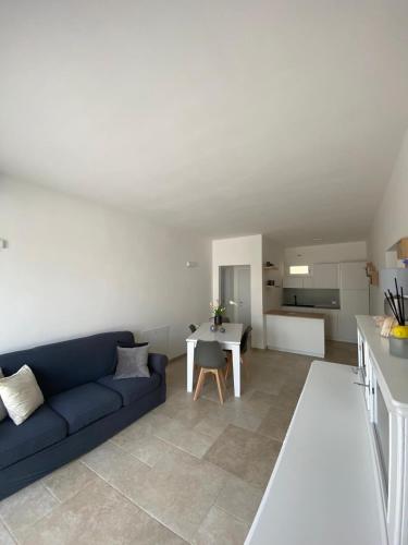 a living room with a blue couch and a kitchen at Country House in Torre San Giovanni Ugento