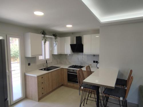 a kitchen with white cabinets and a table and chairs at inas apartments 2 in Lefkímmi