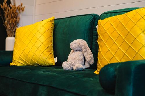 a teddy bear sitting on a green couch with yellow pillows at Kite Lodge in Little Bytham