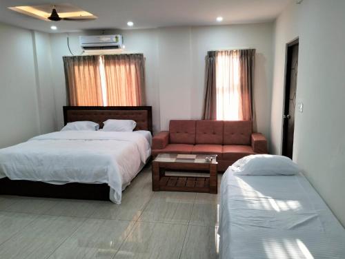 a bedroom with a bed and a couch and a table at Amma Inn Elegance Suites and Apartments in Mysore