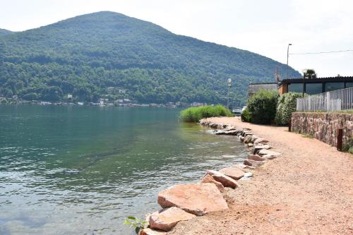 a river with a retaining wall next to a mountain at ZARA HOUSE - Lake and Pet Friendly in Brusimpiano