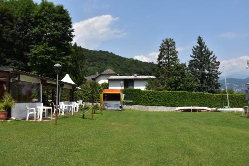 a yard with white tables and chairs and a house at ZARA HOUSE - Lake and Pet Friendly in Brusimpiano