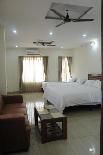 a large bedroom with two beds and a couch at Amma Inn Elegance Suites and Apartments in Mysore