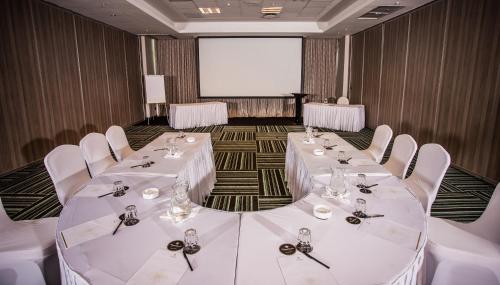 a conference room with white tables and chairs and a screen at Coastlands Umhlanga Hotel and Convention Centre in Durban